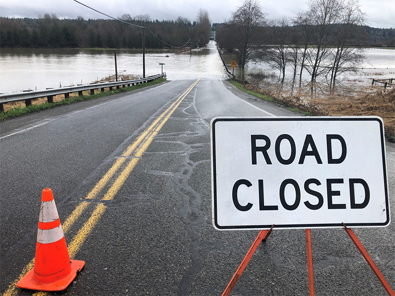 A "road closed" sign next to an orange cone on a King County road