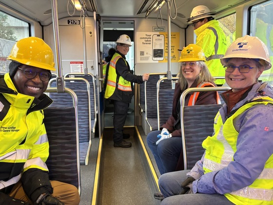 Three people in yellow safety vests on board a light rail train
