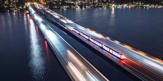 A light rail train crosses the I-90 bridge at night