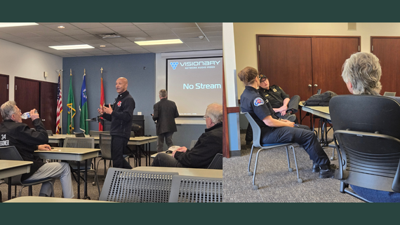 Left: Redmond Fire Chief Adrian Sheppard stands speaking. Right: Chair Perry speaks with two members of Redmond Fire Department.