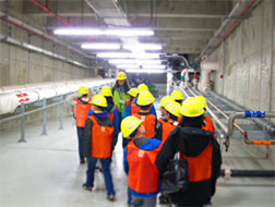 Kids wearing hardhats tour a wastewater treatment facility