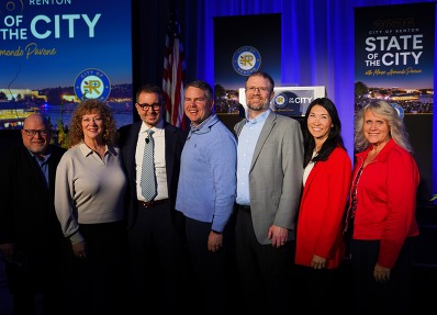 Councilmember Fain in front of a stage with six individuals