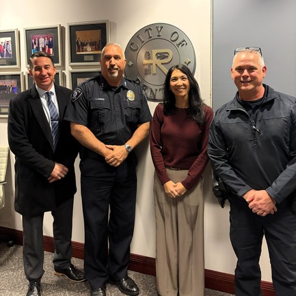 CM. Fain standing with three individuals in front of a city of renton sign