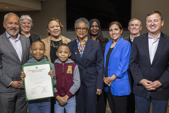 A group of adults and two children posing for a photo, with one child holding the Proclamation document.