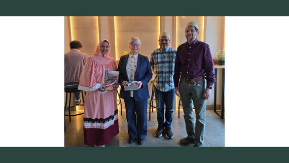 Four people stand smiling in a cafe.