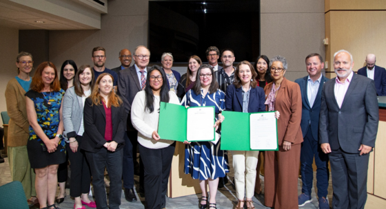 Picture of a group of people including councilmembers and judges holding up printed recognitions in the King County Council chambers.