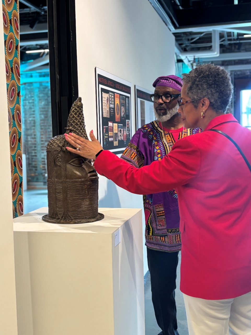 Photo of CM Rhonda Lewis touching a sculpture with another man in the background.