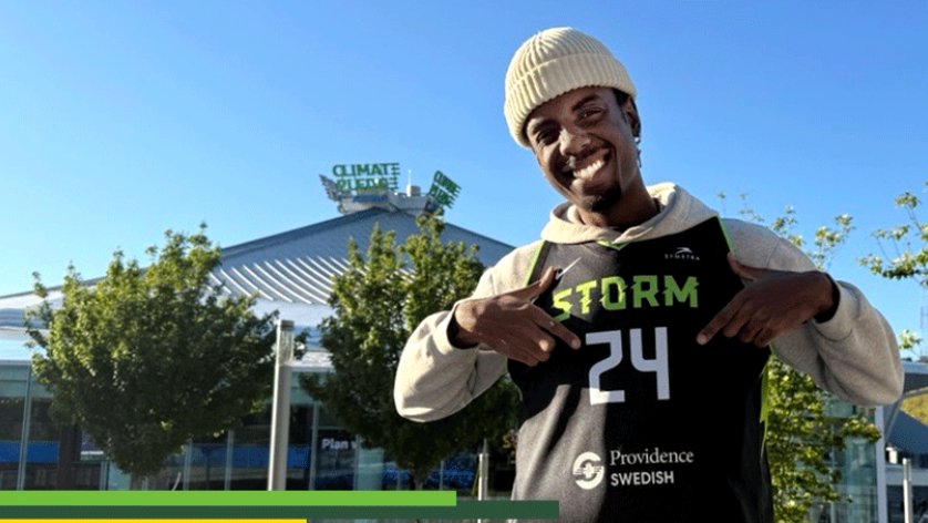 photo of someone standing in front of the climate pledge arena wearing a storm jersey 