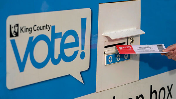 Closeup of a ballot being inserted into a ballot drop box.