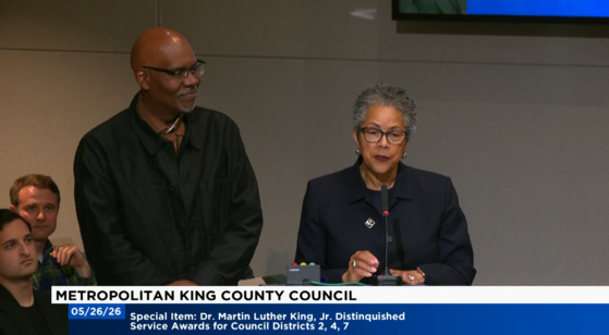Screenshot showing Rhonda Lewis and Gregory Davis at a podium in council chambers