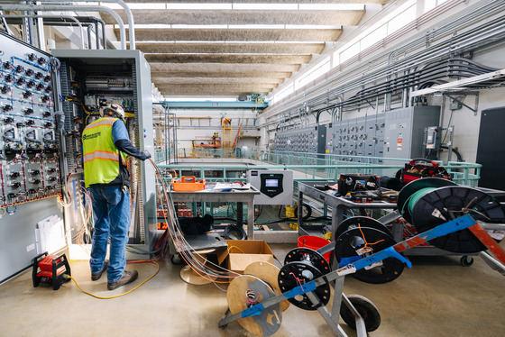 worker wearing personal protective equipment holds wires on site of a raw sewage pump replacement project