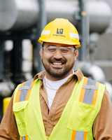 Julio Rodriguez, smiling and wearing a yellow hard hat and orange vest.