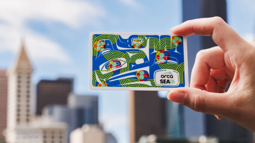 background of the Seattle skyline and a hand holding a special edition ORCA card with a soccer theme