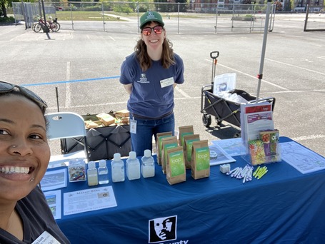 Two WTD employees at a community event smile while standing at their table with information our regional wastewater system.