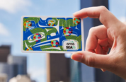 Image of a limited-edition ORCA card with a colorful abstract design featuring blue, green & orange elements against a blurred cityscape background.