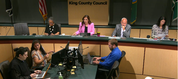 A photo showing councilmembers sitting on the dais with clerks in front.
