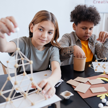 Photo showing two middle-school-aged kids doing arts and crafts.