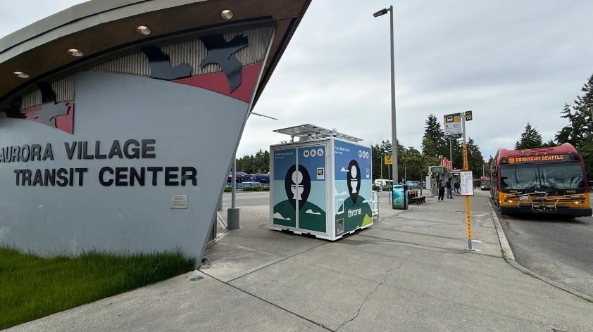 sign for "Aurora Village Transit Center" two toilets and a RapidRide E Line