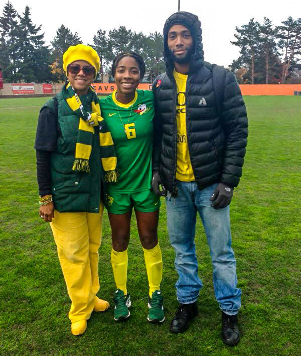 photo of three people standing together on a soccer pitch