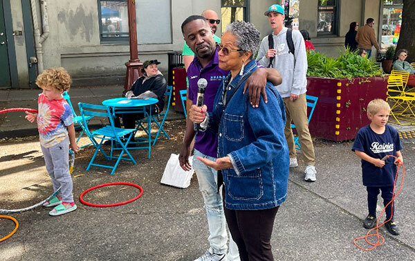 CM Rhonda Lewis stands with a man in the street talking into a microphone