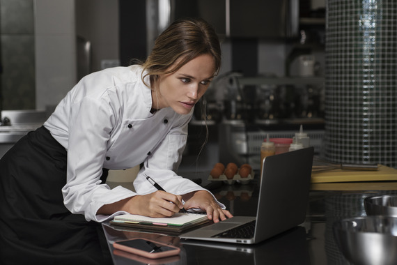 Female chef in the kitchen using laptop device