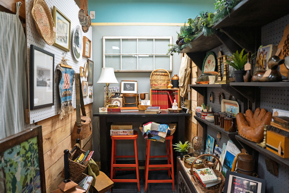 A corner with a shelf, dresser, and wall crowded with trinkets, decor, and framed photographs. 