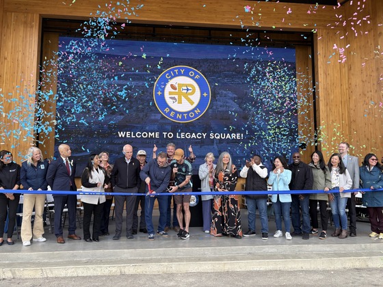 Group of people cutting a ribbon in front of a screen stating Welcome to Legacy Square - City of Renton