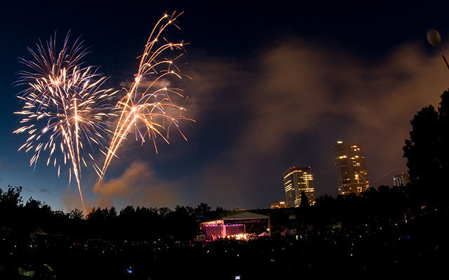 Orange fireworks explode against a dark sky with skyscrapers in the background