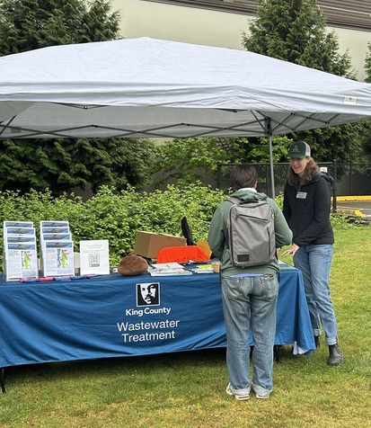A project outreach team member talks with a community member at an in person event in the project area.