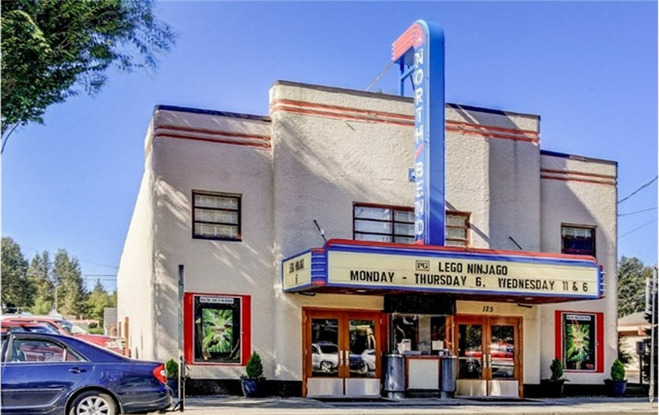 Old, white concrete building with a marquee at the front and a neon sign reading North Bend.