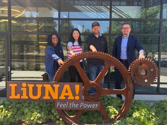 Councilmember Fain with three individuals in front of a wheel with a sign saying LiUNA! Feel the Power