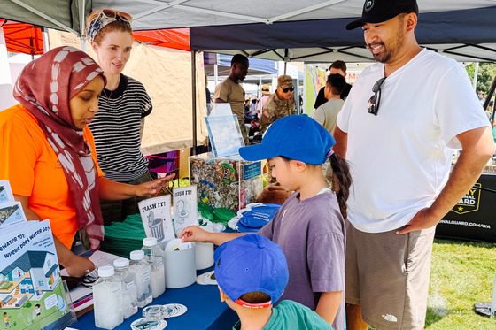 Visitors interact with staff at a booth featuring wastewater education displays.