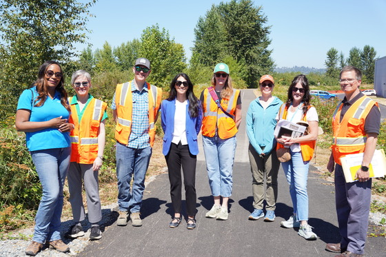 CM. Fain standing outside on a trail with seven other people in orange construction vests