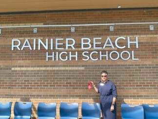 CM Lewis stands before the NEW Rainier Beach High School  with a piece of the ribbon from the official ribbon cutting ceremony.