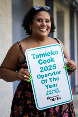Smiling person holding a Metro placard that reads “Tamieko Cook 2025 Operator Of The Year.” 