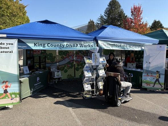 A photo of a community member and project team member talking at the King County Department of Natural Resources Booth at Salmon Days 2025