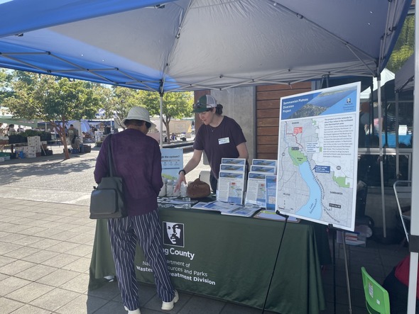 A photo of a community member and King County Wastewater Treatment Division Representative talking at the Sammamish Farmers Market