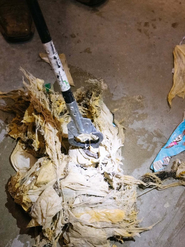 A photo of a large wet clog of wipes twisted up beneath a claw grabber tool