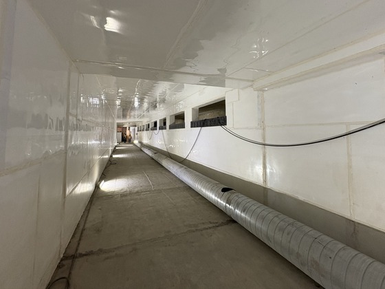 Interior of a passive weir channel with rectangular holes along the right-side wall to allow wastewater through.