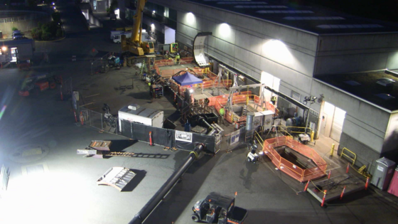 Nighttime overhead view of the EPS gate replacement work site. A piece of a cofferdam is being raised by a crane.