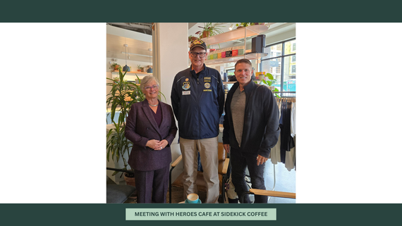Three people stand in a coffeeshop smiling for a photo.