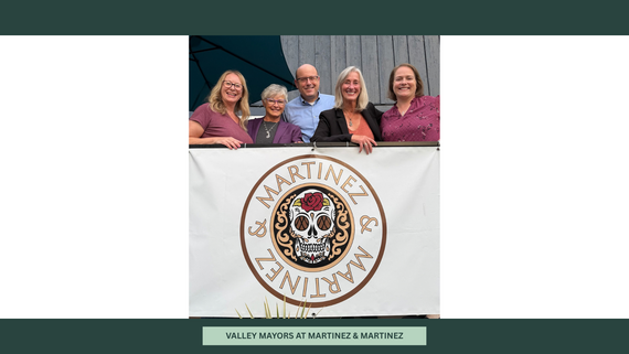 Five people stand, smiling for a photo, behind a sign banner with a logo featuring calavera (skull) and the text "Martinez & Martinez".