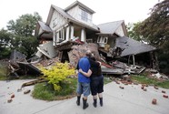 man and women standing in front of destroyed home