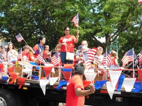 people on holiday float raise American flags