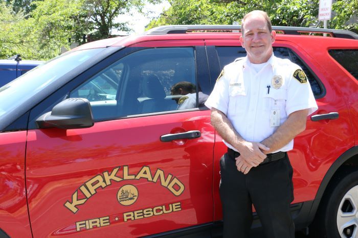 Deputy Chief Bill Newbold posing in front of a Kirkland Fire Department vehicle