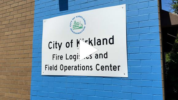 Image shows white "City of Kirkland Fire Logistics and Field Operations Center" sign against a blue brick wall