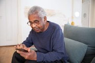 Photo of man sitting on couch lookin at phone