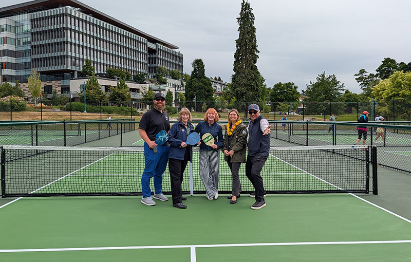 Photo of 5 people standing on a pickleball court