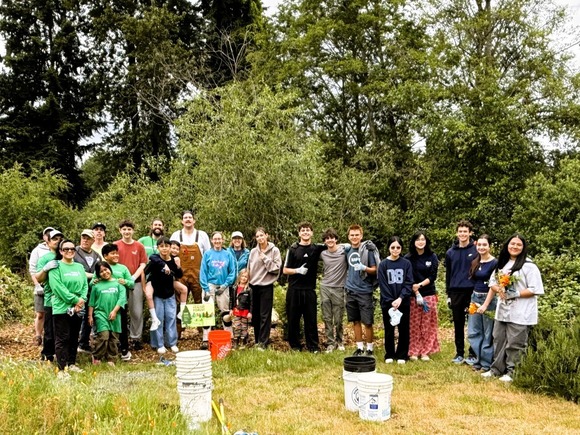 Photo of a group of people standing outside with gardening tools
