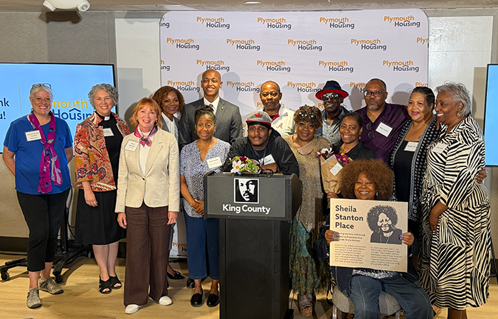 Photo of a group of people standing and sitting, with one person holding a plaque